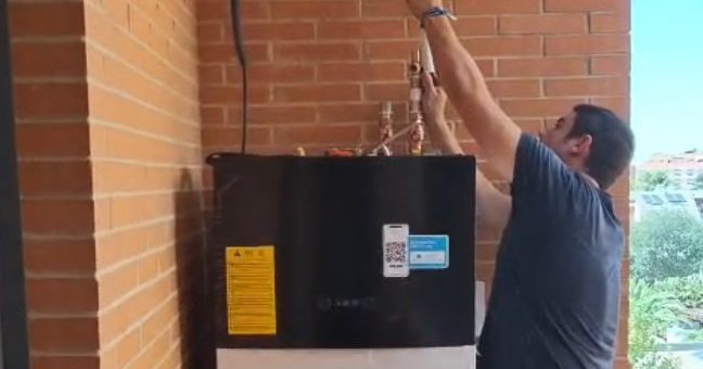 Instalador conectando las tuberías de una unidad de aerotermia en Madrid