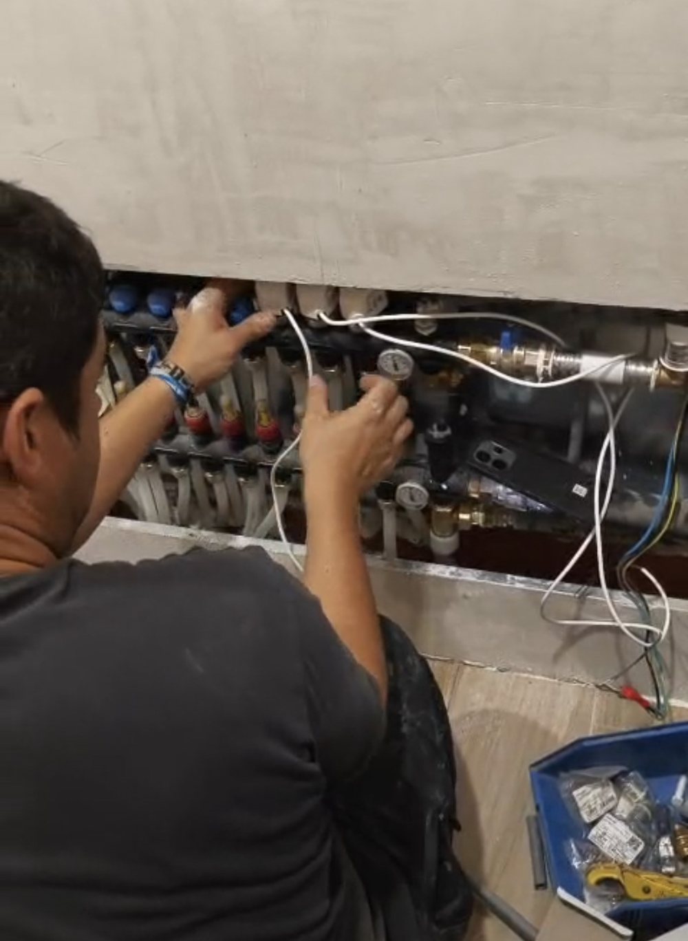 Técnico conectando los actuadores del colector de suelo radiante de una instalación de aerotermia en Madrid